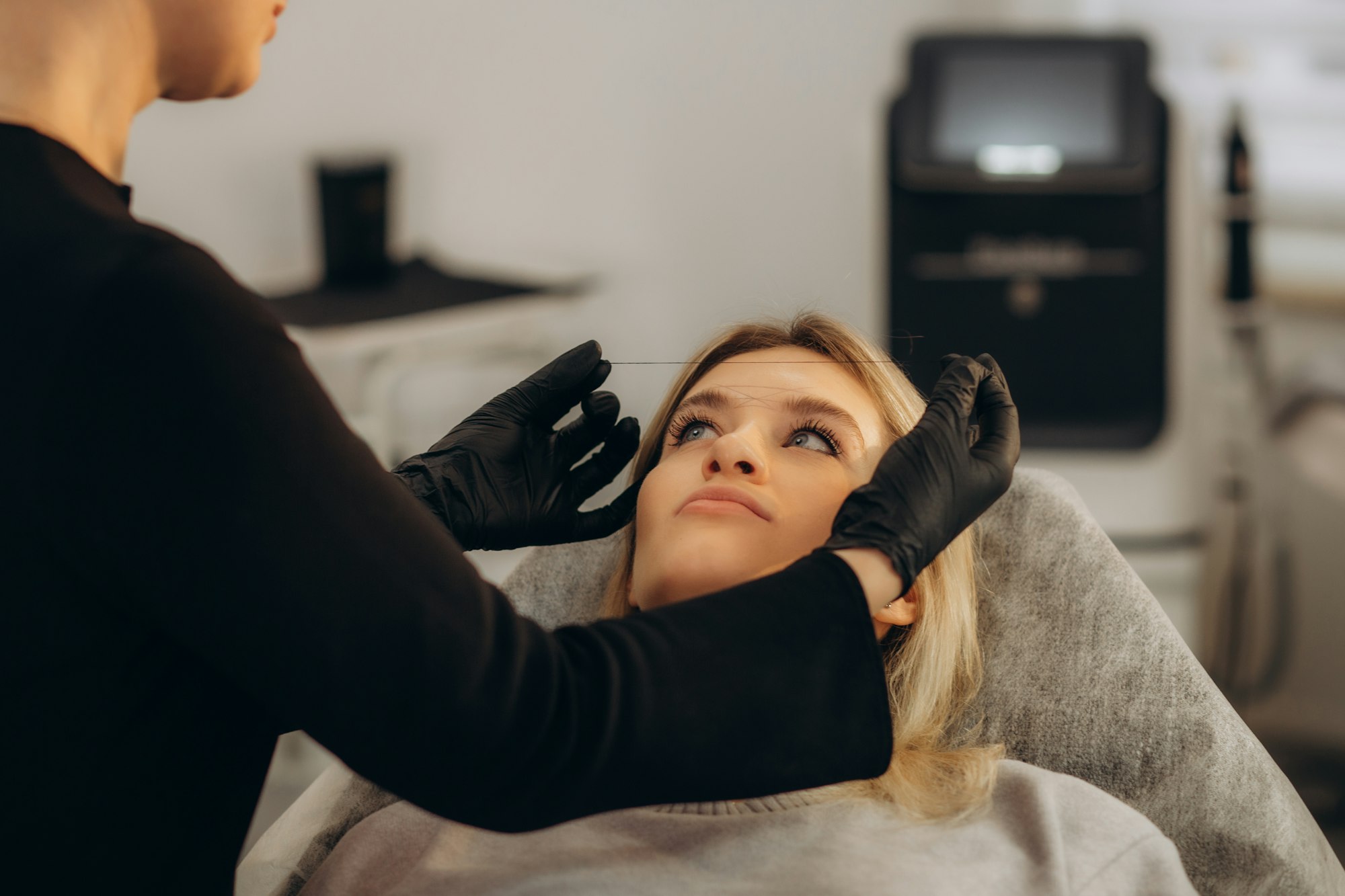 The make-up artist plucks eyebrows with a thread close-up. Women's cosmetology in the beauty salon.